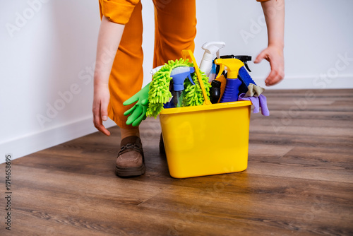Foto Woman housemaid placing yellow bucket with chemicals on floor