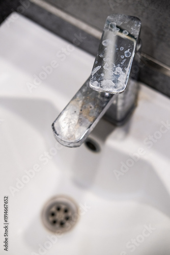 A dirty metal faucet in the sink with limescale, rust marks, and grime around the mixer, showing neglect and the need for cleaning.