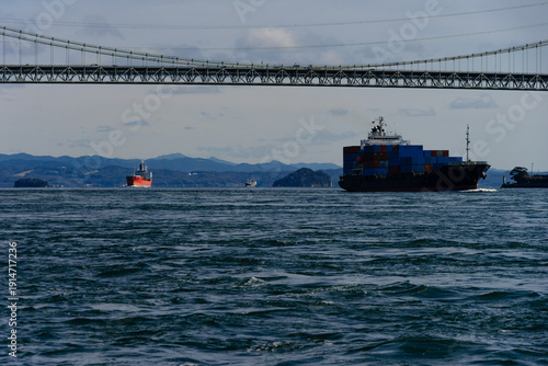 関門橋と関門海峡の波間に進むコンテナ船と満珠干珠20240224-1
