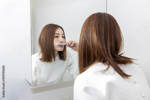 鏡を見て歯磨きする女性