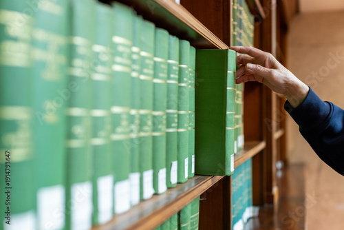 Canvastavla Hand selecting book from wooden library shelf