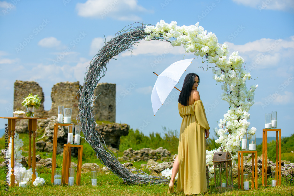 Obraz premium Elegant bride woman under wedding arch. Romantic wedding arch outdoor scene. Bride under floral wedding decor. Luxury wedding arch with flowers. Beauty bride ceremony concept.