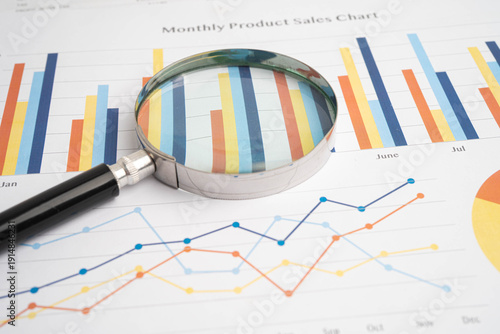 Magnifying glass on charts graphs paper.