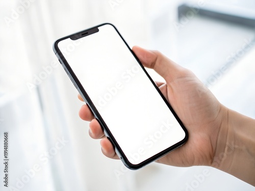 Close-up of a hand holding a modern smartphone with a blank white screen, perfect for app development mockups or website previews.
