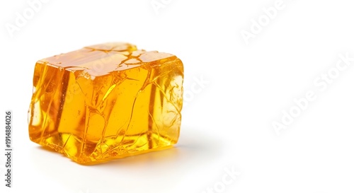 Close up of a golden translucent jelly cube on a white background