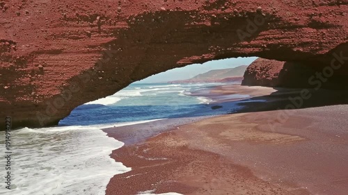 Flying through the arch on Legzira beach with arched rocks on the Atlantic coast in Morocco, 4k