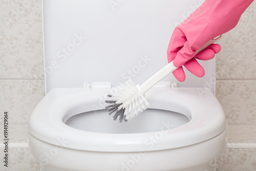 Bilde på lerret Woman hand in pink rubber protective glove holding brush and cleaning white toilet
