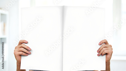Hands holding a blank white double page newspaper spread mockup for design presentation.
