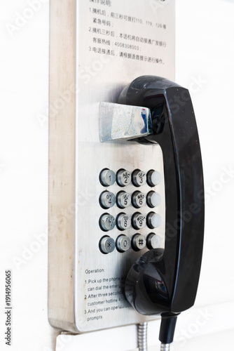 Slika na platnu Vintage Wall-Mounted Payphone with Black Handset and Metal Dial Pad in Office Se