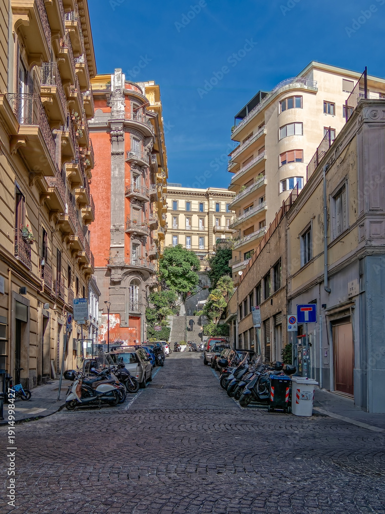 Obraz premium Authentic urban scene in Naples, Italy. Vertical shot of a narrow street with historic apartments, cobblestone road, and traditional Neapolitan life in the Chiaia neighborhood.