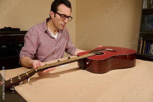 Fotografie Man Adjusting Guitar Strings During Acoustic Guitar Maintenance And Repair