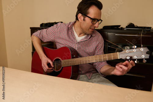 Obraz na plátně Man Adjusting Acoustic Guitar Strings at Home — Guitar Maintenance and Repair Pr