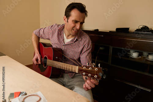 Obraz na płótnie Man Changing Guitar Strings and Tuning an Acoustic Guitar for Maintenance and Re