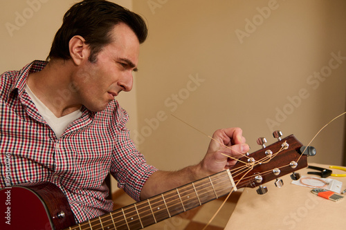 Fotografie Man Changing Guitar Strings and Repairing Acoustic Guitar Headstock During Maint