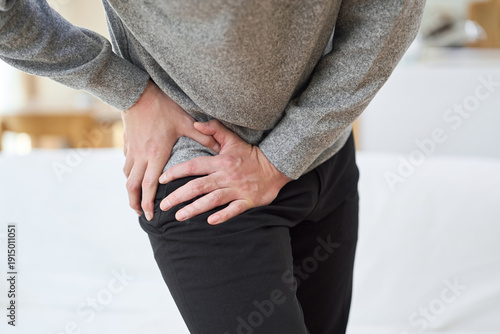 Foto 股関節が痛くて苦しむアジア人男性