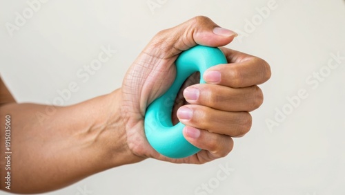 Wallpaper Mural Hand squeezing a turquoise stress ball, showing hand veins and muscle tension against a plain white background. Torontodigital.ca