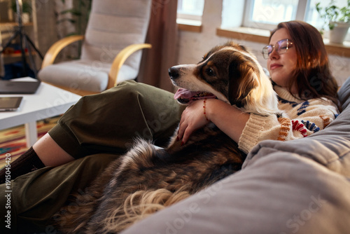 Εκτύπωση καμβά Woman resting on couch with dog in warm evening light