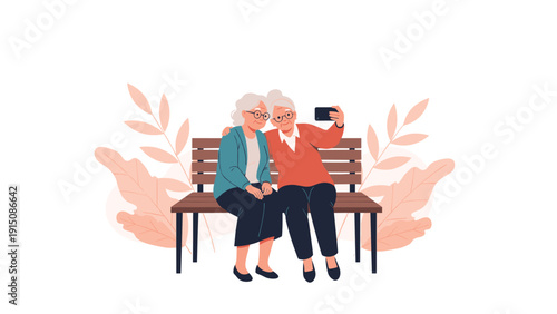 Two elderly women sit together on a park bench and smile while taking a fun selfie with their smartphone.