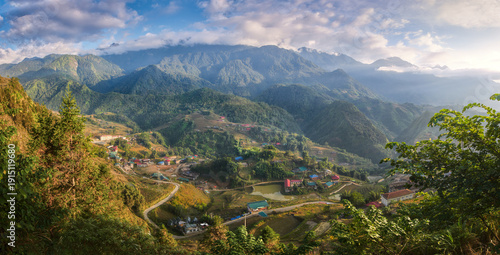Panoramic view on serene morning hills with clouds illuminated by soft sunlight in village near in popular tourist destination of Sapa, North Vietnam.