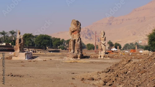 Damaged Colossi of Memnon showing erosion and earthquake damage in Luxor, weathered ancient statues with modern preservation efforts