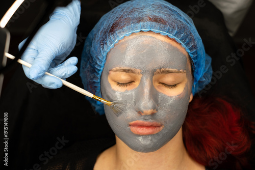 In the cosmetologist's office, a mask is applied to the girl's face. Spa treatments, skin care, moisturizing and rejuvenation