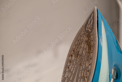 Fotografie Dirty steam iron soleplate with burnt stains close up