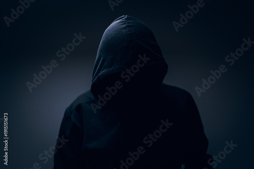 Εκτύπωση καμβά Dark hooded silhouette emerging from shadows, anonymous and enigmatic portrait symbolizing mystery, secrecy, tension, and the unknown