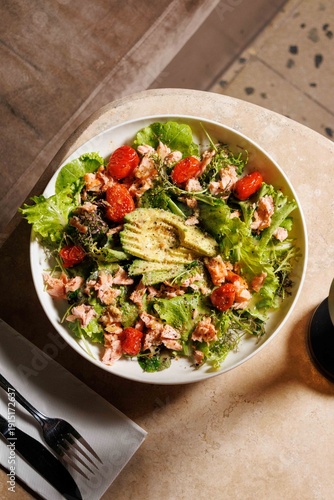 Fotografía Salmon avocado salad in a dark, cozy restaurant