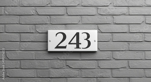 Architectural style grey brick wall with white plaque showing house number twenty four