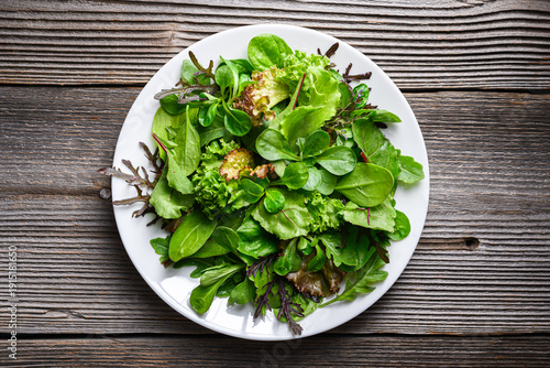Foto Green salad leaves arranged on white plate in minimal style
