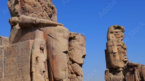 Colossi of Memnon twin guardians at mortuary temple entrance in Luxor Egypt, massive weathered statues of Amenhotep III