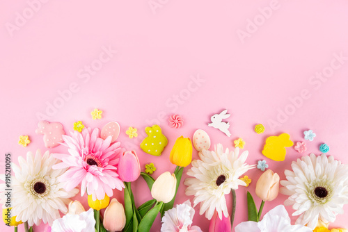 Beautiful spring flowers bouquet with Easter decorations on pink background. Easter holiday flat lay with eggs, rabbits and springtime flowers. Greeting card background with copy space