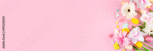 Beautiful spring flowers bouquet with Easter decorations on pink background. Easter holiday flat lay with eggs, rabbits and springtime flowers. Greeting card background with copy space