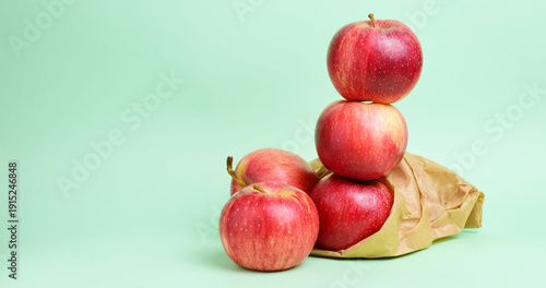 Red apples stacked on a green background, copy space.
