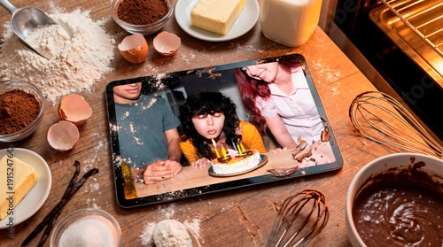 Still life of cake ingredients with final result on digital tablet during birthday candle blowing moment