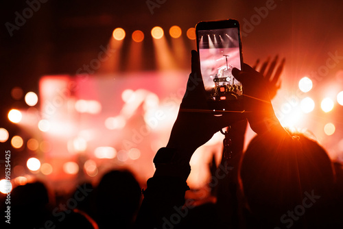 Photography Close up of smartphone recording live band in red concert light