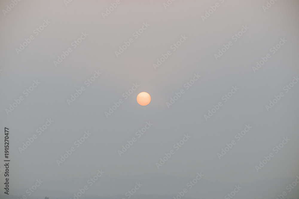 Naklejka premium Orange sun partially obscured by thick wildfire smoke in southern Chile.