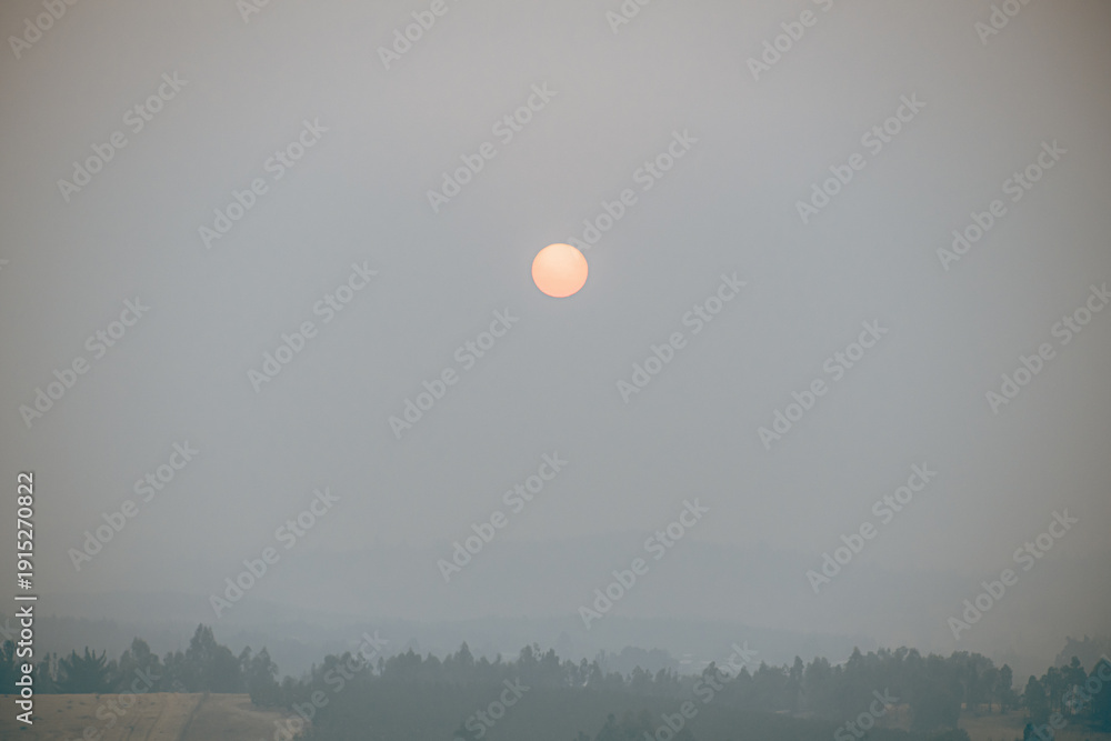 Obraz premium Orange sun partially obscured by thick wildfire smoke in southern Chile.