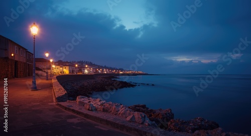 Serene coastal atmosphere with streetlights casting soft light near placid sea