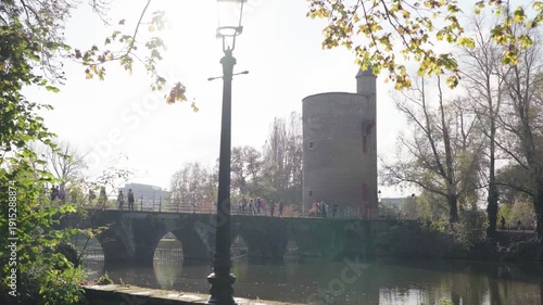 Bridge with castle tower reveal from park bench in Bruges Belgium