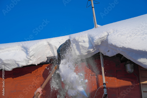 snow drifts on the roof of the house, dangerously overhanging boulders, snow removal with a shovel