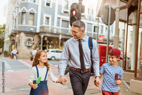 Fotografia Father in business attire walking with children at city crosswalk