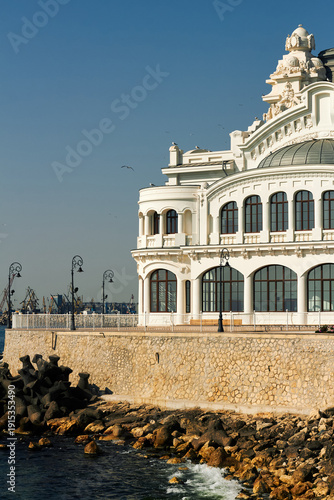 Historic seaside building with ornate architecture overlooking rocky coast and calm sea