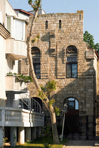 Historic stone facade residential building with arched windows and tree