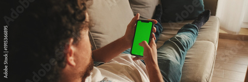 Guy dressed in denim shirt has lunch, sits in the living room and emotionally watches sports game on TV. Panoramic