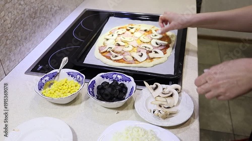 young woman preparing homemade pizza by placing ingredients on fresh dough.