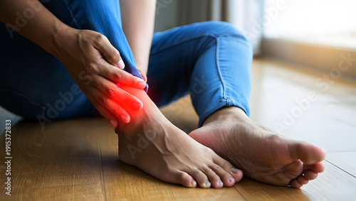 Person with bright red pain indicator on injured ankle sitting on wooden floor injury