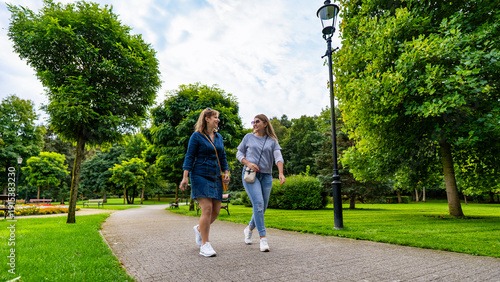 Принти на полотні Two happy middle-aged women walking in city park on spring day