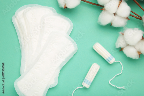 Sanitary pad and cotton flower on mint background. Daily feminine hygiene product. Menstruation and womens health concept. Copy space.