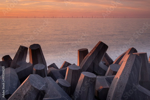 Concrete Sea Defences on Llanddulas Beach backed by the distant Gwynt y Mor Offshore Wind Farm at sunset, Llanddulas, near Abergele, Conwy County Borough, North Wales, UK